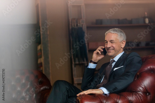 Smiling businessman talking on cell phone in menswear shop photo