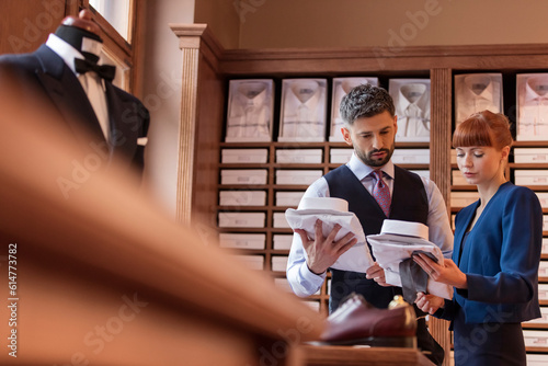 Fotografie Worker showing businessman dress shirts in menswear shop
