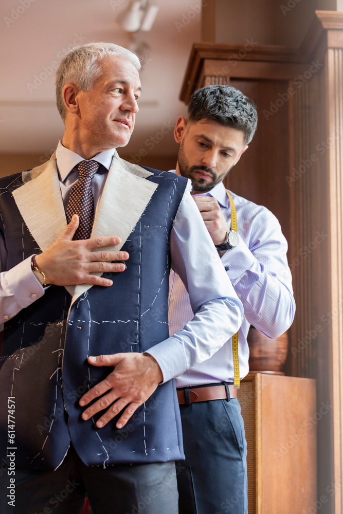Tailor fitting businessman for suit in menswear shop - obrazy, fototapety, plakaty 