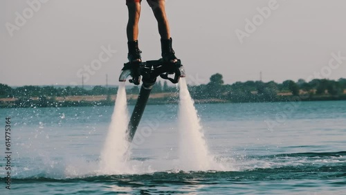 Man flying at the aquatic flyboard in slow motion. Large jet of water under high pressure propels a person above the water. Active people enjoy extreme water sports water sport. Lifestyle, Recreation photo