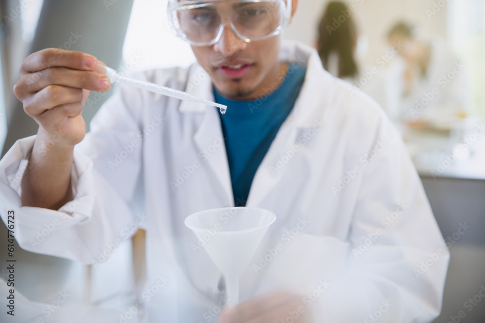 Male college student conducting scientific experiment using pipette in ...