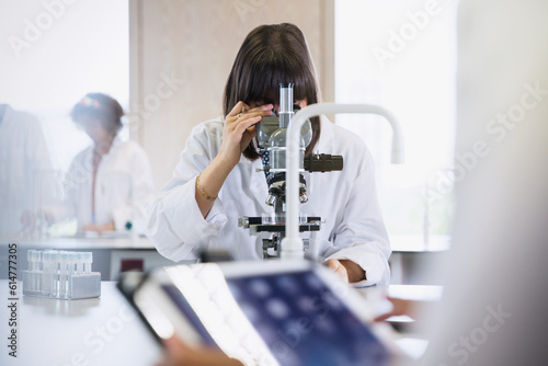 Female college student using microscope in science laboratory classroom photo