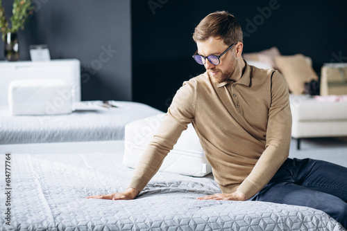 Man bying new bed with orthopedic pillow in furniture store photo