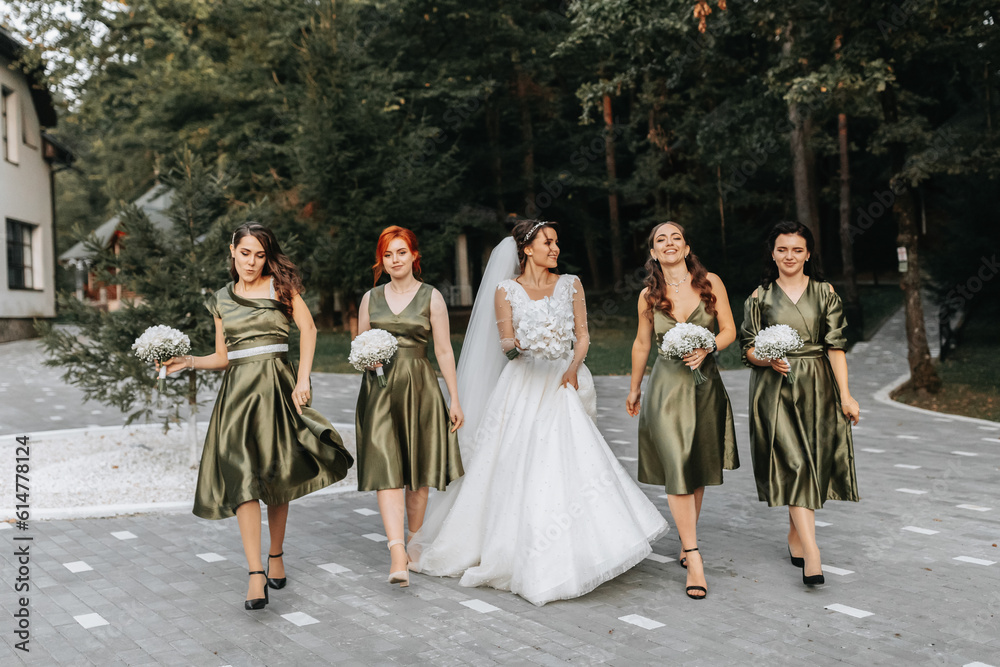 Beautiful bride and her friends- bridesmaids having fun after wedding ceremony. Happy girls at their best friend's wedding. Beautiful and elegant bride with bridesmaids walking on the stairs