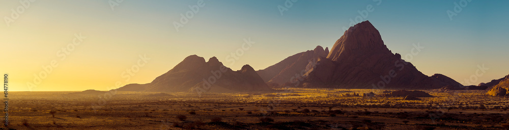 Naklejka premium Mountain landscape of Spitzkoppe peaks on sunrise, panorama of a stone desert in morning soft light, Namibia. Travelling and adventures to wildlife.