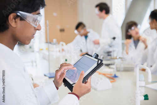Male college student using digital tablet in science laboratory classroom