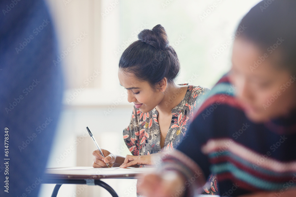 Female college student taking test at desk in classroom Female college student taking test at desk in classroom