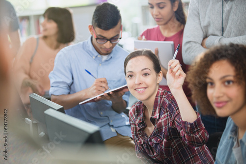 College student raising hand in computer lab classroom