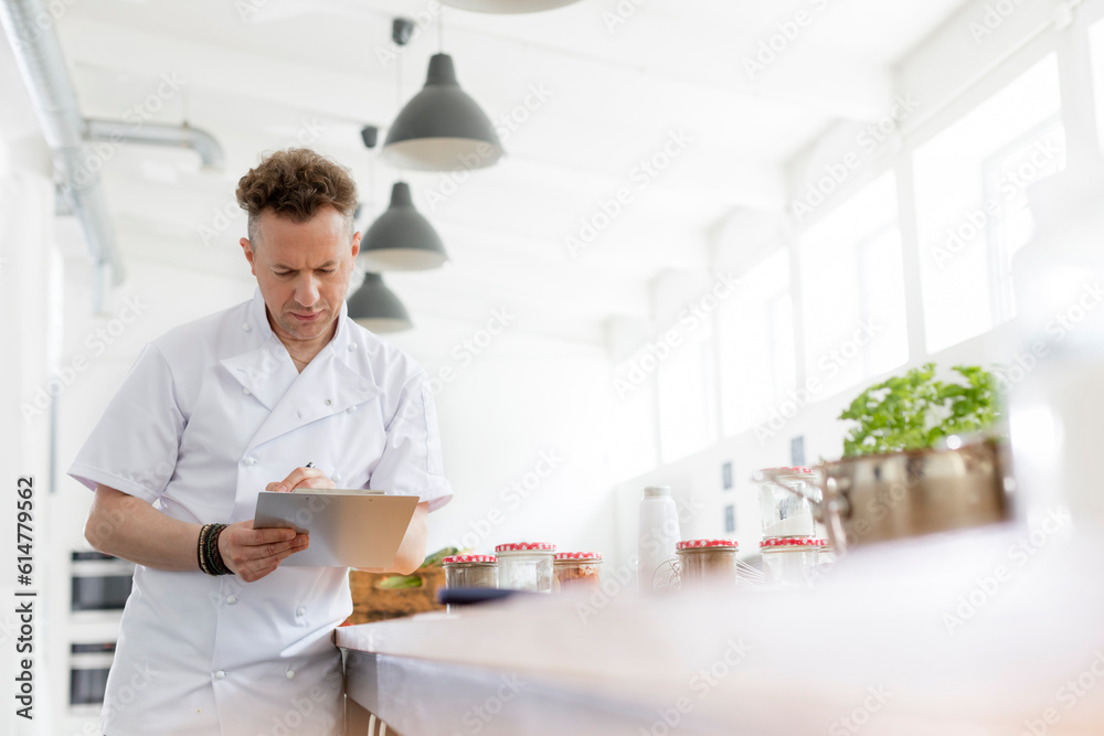 Chef teacher preparing with clipboard in cooking class kitchen Chef teacher preparing with clipboard in cooking class kitchen