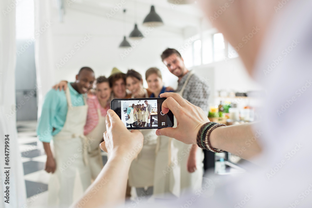 Obraz premium Man photographing cooking class students in kitchen