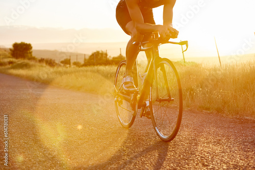 Male cyclist riding bike on sunny sunrise rural road