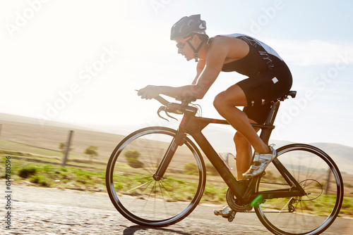 Male triathlete cyclist cycling on sunny rural road at sunrise