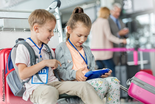 Brother and sister using digital tablet in airport departure area