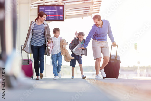 Family walking pulling suitcases at train station
