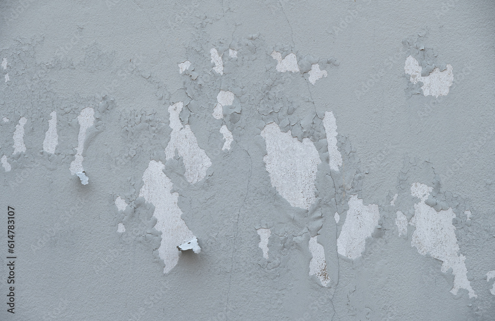 Peeling paint on gray concrete wall. Peeling, cracking, or blistering