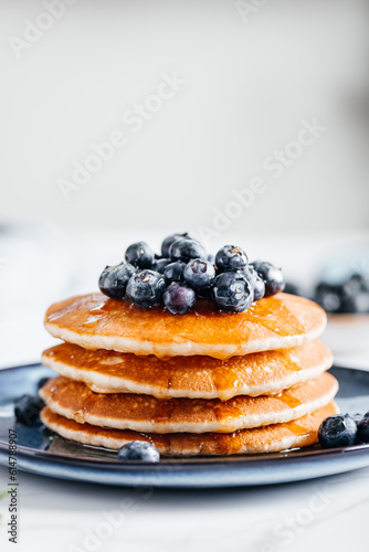 Fresh American Pancakes with blueberries and maple syrup on blue plate