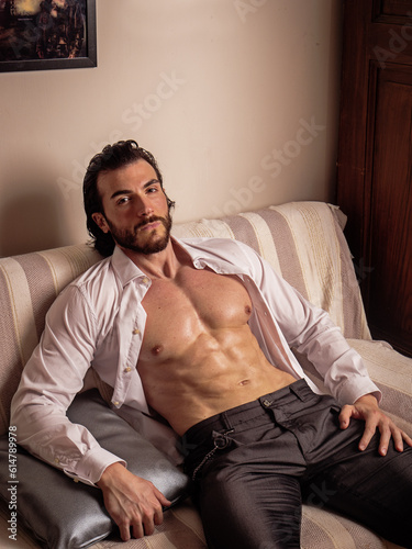 Shirtless muscular young man at home on couch