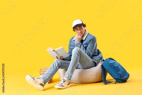 Male student reading book on yellow background © Pixel-Shot