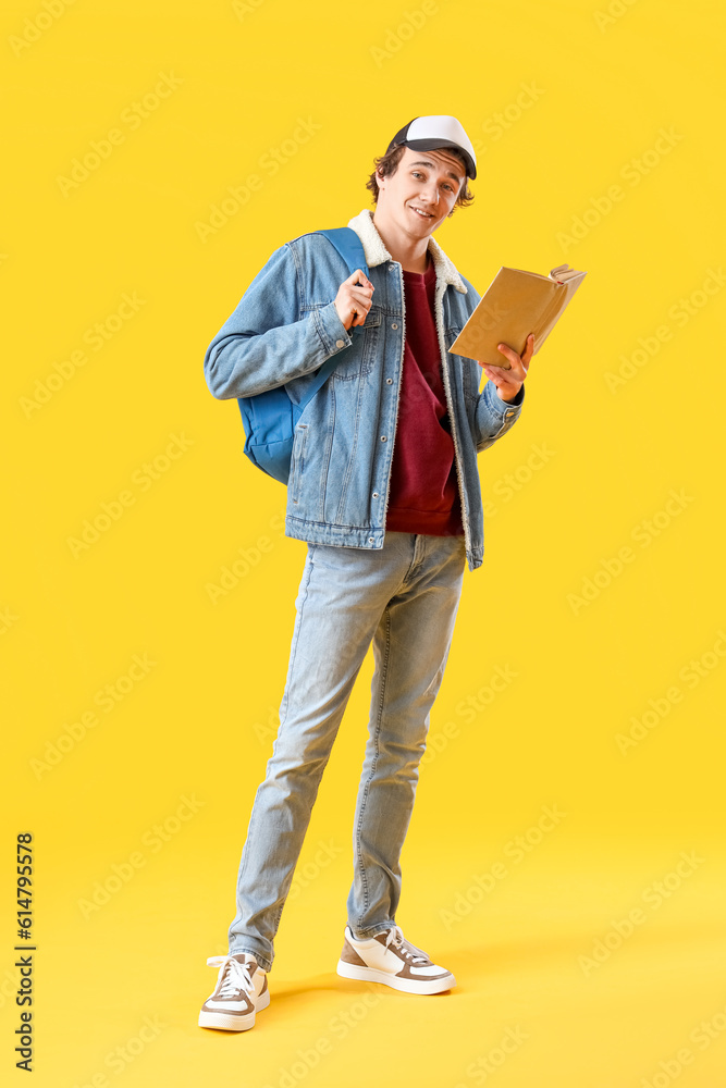 Male student reading book on yellow background Male student reading book on yellow background