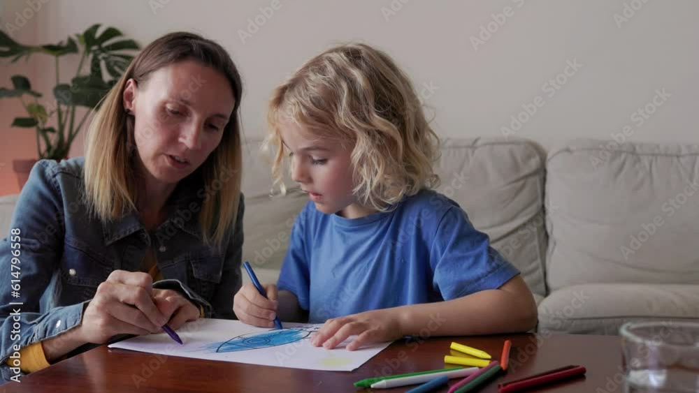 Mother and son child drawing together having fun inside home living room Mother and son child drawing together having fun inside home living room