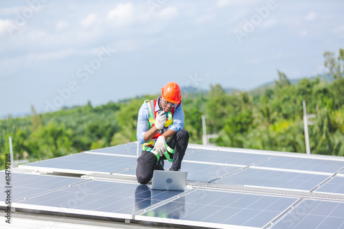 African American engineer maintaining solar cell panels on factory building rooftop. Technician working outdoor on ecological solar farm construction. Renewable clean energy technology concept © chokniti