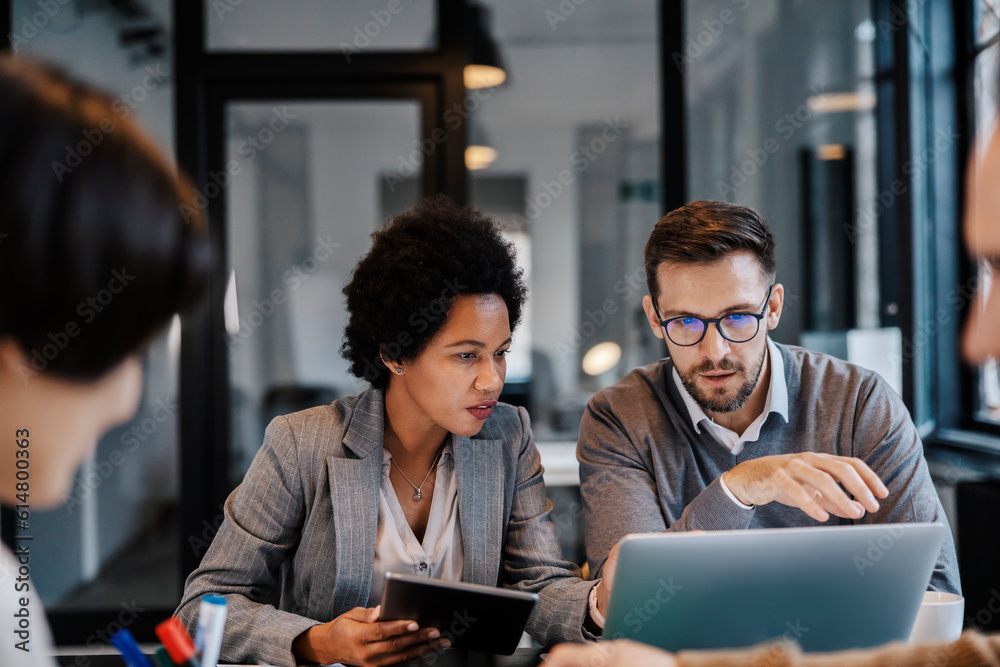 The interracial executives are sitting at the boardroom and solving problems about project on a laptop and tablet. The interracial executives are sitting at the boardroom and solving problems about project on a laptop and tablet.