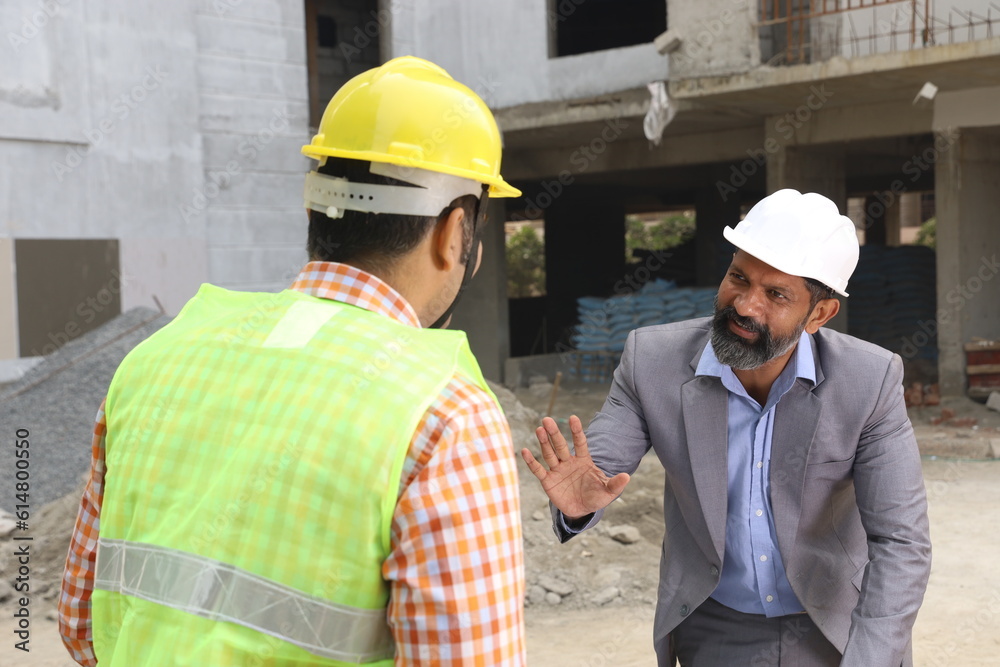 Hardworking Indian Site engineer and manager analyzing the blueprint and figuring out the work in progress. Reporting the inspector. Hardworking Indian Site engineer and manager analyzing the blueprint and figuring out the work in progress. Reporting the inspector.