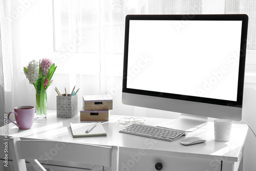 Comfortable workplace with modern PC and beautiful hyacinth flowers near window