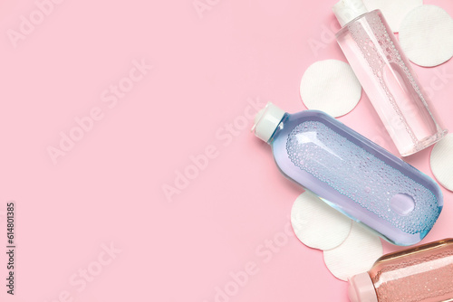 Fotografija Bottles of micellar water with cotton pads on pink background
