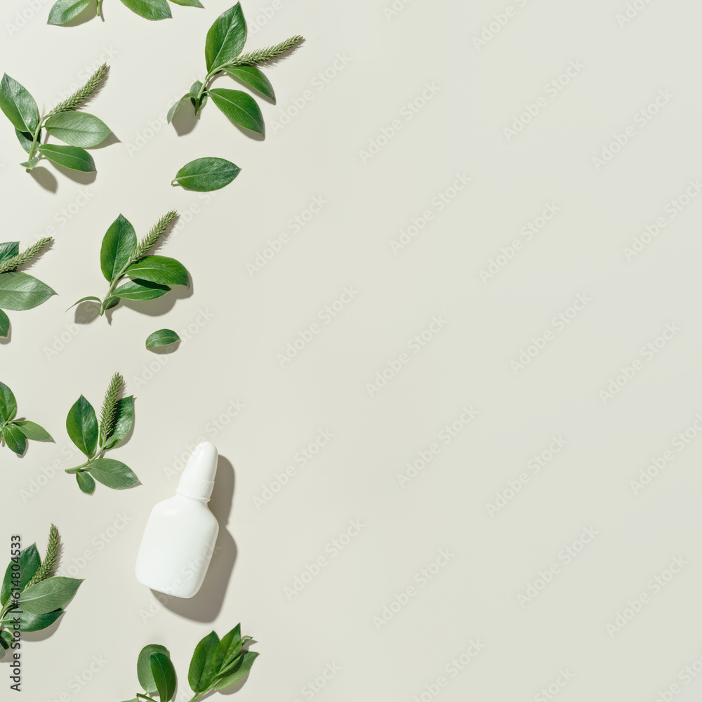 Seasonal spring allergies, fresh spring blooming branches tree with green new leaves and mock up white nasal spray bottle, beige background, top view trend pattern, Seasonal allergy concept