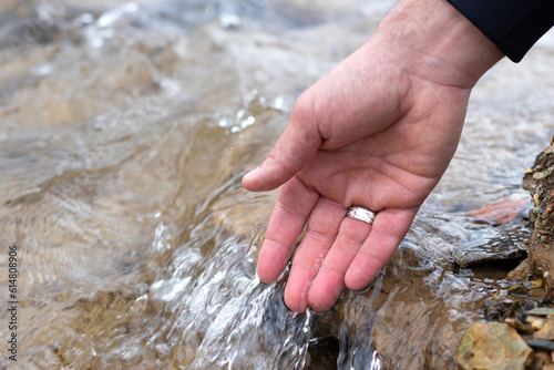 Male hand touching clean, fresh water in nature. A close-up.