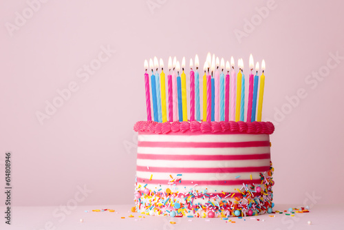 Pink and white striped birthday cake with lots of candles