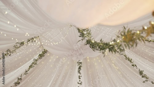 Beautiful lighting of the wedding tent with the decoration of fresh flowers