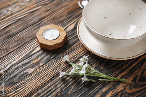 Plates with flowers and candle on brown wooden background