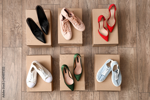 Cardboard boxes with different female heeled shoes and sneakers on wooden background