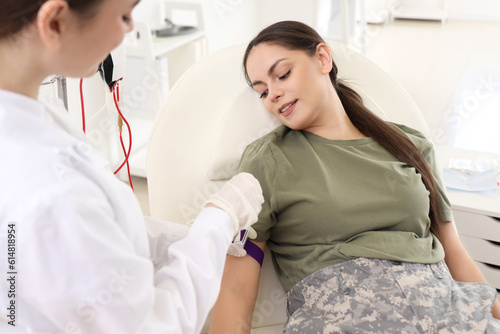 Doctor preparing female soldier for blood transfusion in clinic