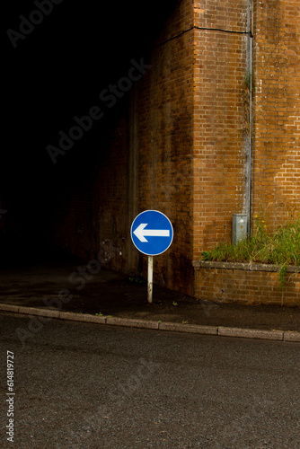 Directional arrow road sign under bridge