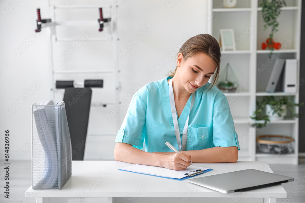 Female medical intern writing in clipboard at hospital Female medical intern writing in clipboard at hospital