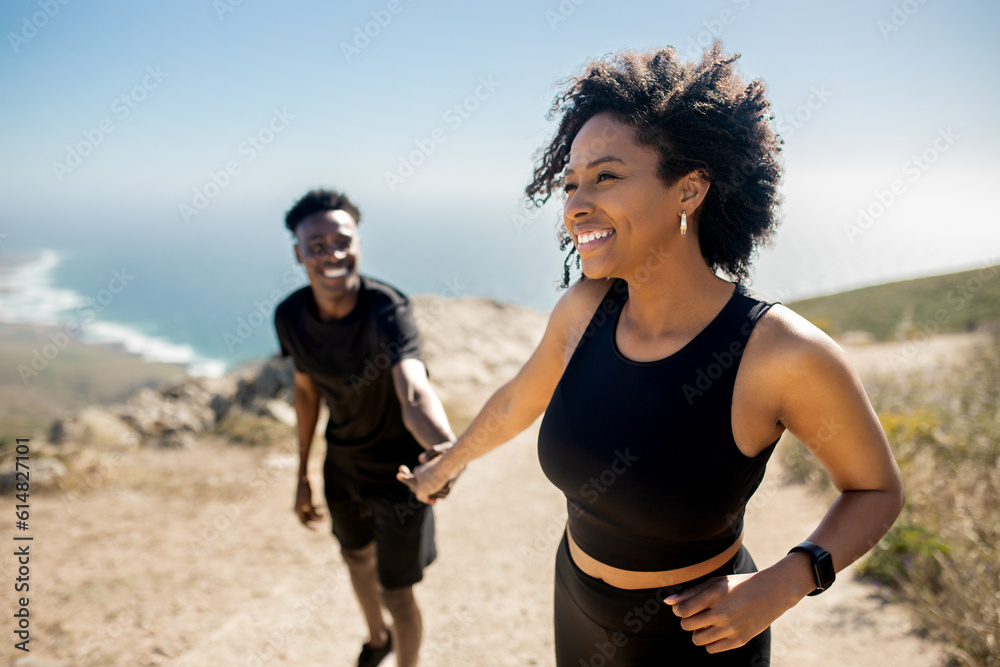Happy black lady leading man by hand on rocks near ocean, enjoy break from morning workout outdoors