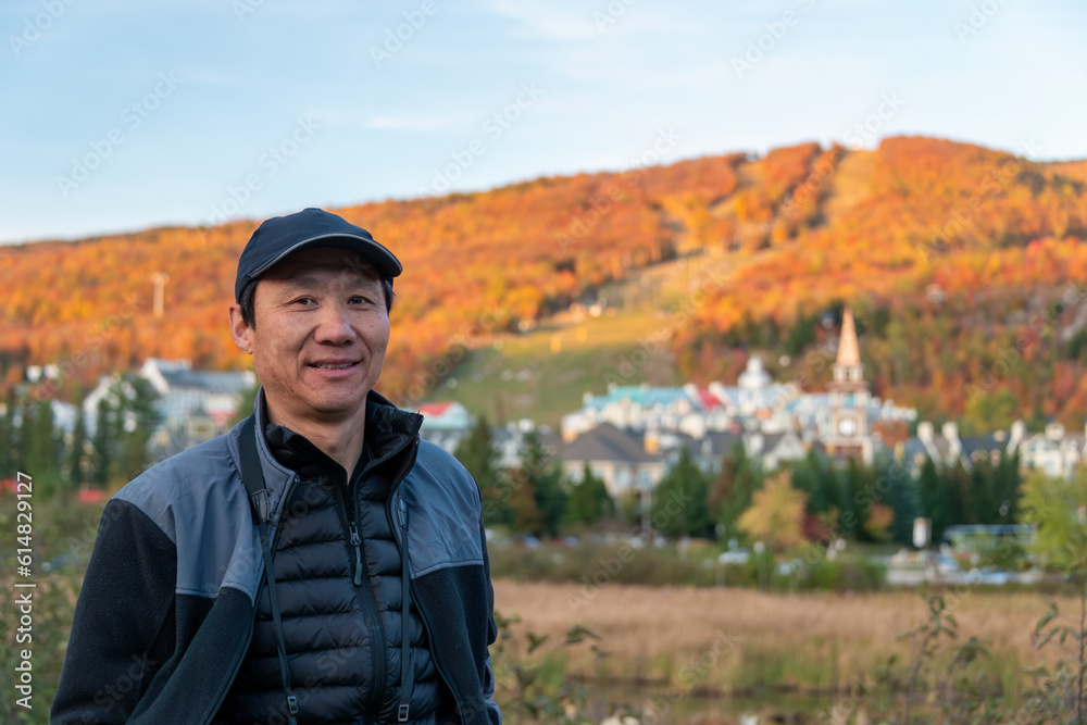 Tourist posing for photos in front of Mont Tremblant village in Autumn, Quebec, Canada.