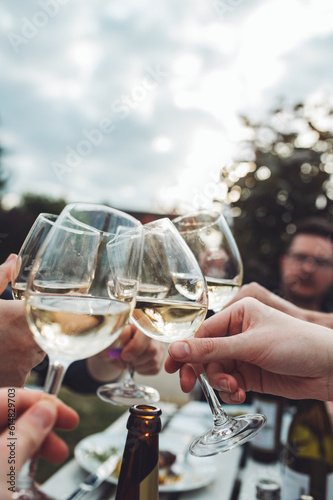 Freunde stoßen an einem lauen Sommerabend mit Weißwein an photo