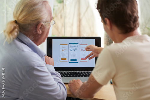 Young man teaching granddad how to pay for online subscription