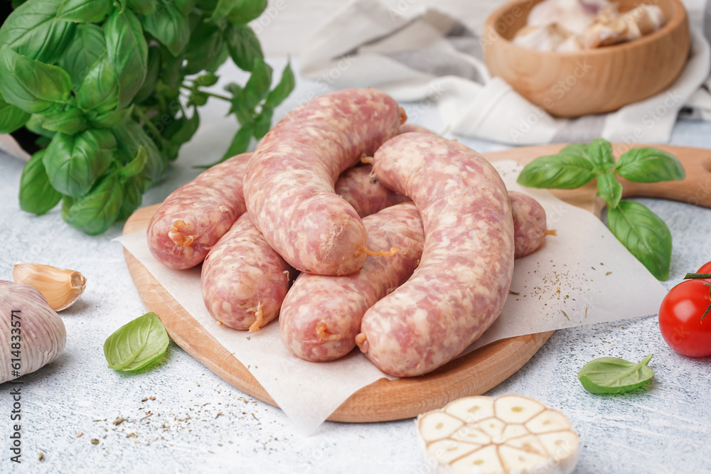 Wooden board with raw homemade sausages on light background Wooden board with raw homemade sausages on light background