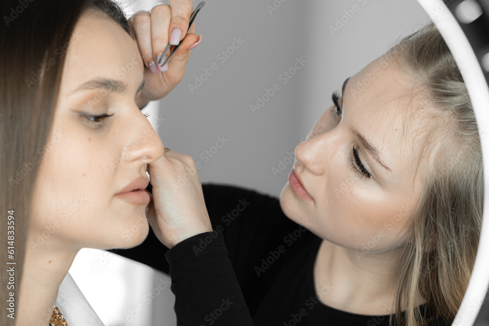 The photo conveys the skill of makeup artist who improves shape eyebrows, giving them sophistication and clarity. This process is an important step for creating impeccable image client in beauty salon The photo conveys the skill of makeup artist who improves shape eyebrows, giving them sophistication and clarity. This process is an important step for creating impeccable image client in beauty salon