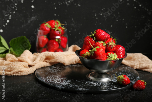 Bowl and glass with fresh strawberries on black background