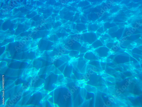 Dark blue ocean surface seen from underwater. Abstract waves underwater and rays of sunlight shining through, Sun light rays undersea deep, Underwater background with sea bottom, Mediterranean sea