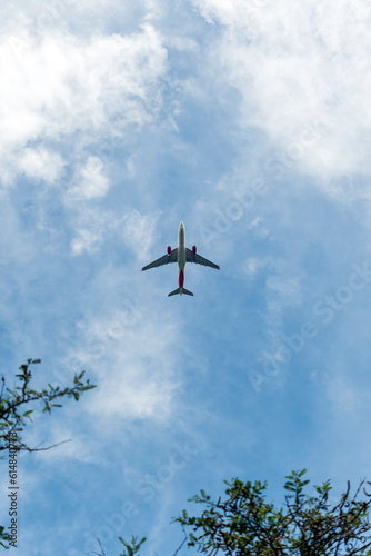 Avión en el cielo azul con nubes desde abajo, avión de pasajeros de alto vuelo. 