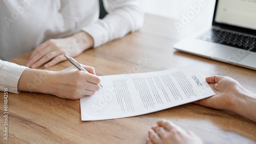 Business people signing contract papers while sitting at the wooden table in office, closeup. Partners or lawyers working together at meeting. Teamwork, partnership, success concept