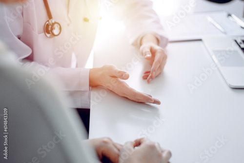 Doctor and patient discussing current health examination while sitting at the desk in clinic office  closeup. Medicine concept
