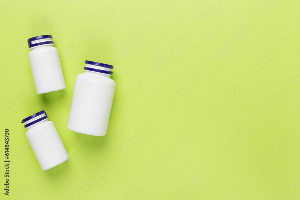 Fototapeta premium Plastic bottles with vitamins on color background, top view